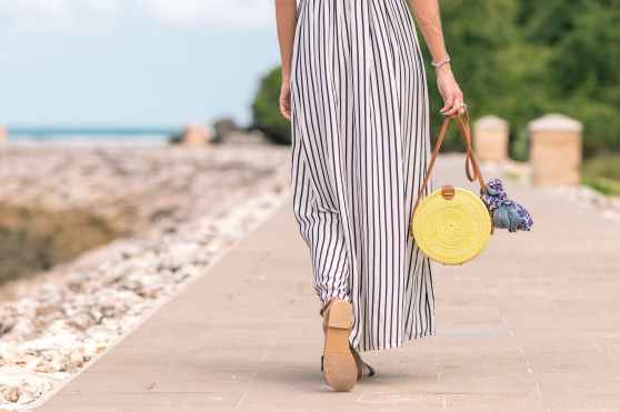 woman wearing black and white striped maxi skirt holding brown bag